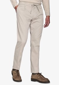 Beige bomuldsbukser med snor i taljen, tapered silhouette, to forlommer og en glat tekstur, parret med brune ruskindsko.