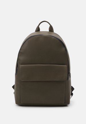Sac à dos vert olive avec une surface lisse et mate ; possède un sommet arrondi, une poche avant avec rabat et des accents de fermeture éclair noirs.