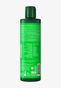 Grüne Plastikflasche mit Pumpenverschluss, versehen mit weißem Text, der Zutaten und Verwendungshinweise auf einer strukturierten Oberfläche auflistet.