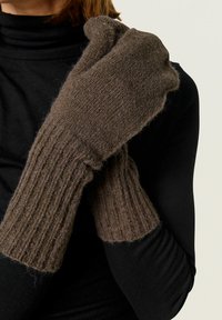 Moufles en tricot marron avec une texture côtelée, en matériau doux, et une coupe légèrement lâche au poignet. Pas de fermetures ou de motifs visibles.