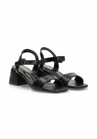 Sandalias de cuero negro con tacón bloque y dos correas anchas. Cuenta con una correa ajustable en el tobillo y una textura suave y mate. Diseño de punta cuadrada.