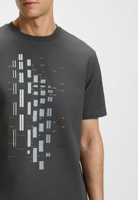 Grå T-shirt med rund hals i mjuk bomull, utrustad med en abstrakt grafisk design med varierande rektanglar i ljusblå och gula accenter.