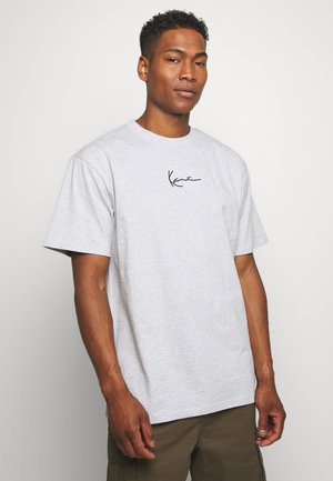 T-shirt en coton gris clair à manches courtes, avec un logo noir en cursif sur la poitrine. Coupe droite et texture douce.