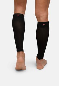 Maniche a compressione nere per gambe realizzate in tessuto traspirante, con texture a costine e polsini elastici, logo visibile nella parte superiore.