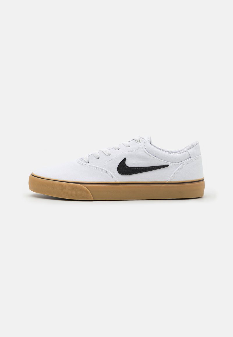 Fehér vászon sportcipők fekete Swoosh-sal, világosbarna gumitalppal, fűzős dizájnnal és megerősített orr résszel. Tiszta vonalak és minimalista stílus.