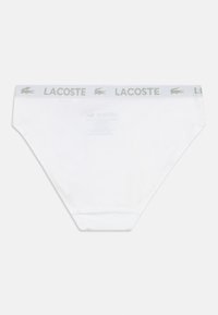 Fehér pamut férfi alsónadrág szürke gumis derékrésszel, rajta "LACOSTE" felirattal és logóval. Egyszerű, sima textúra és standard alsónadrág forma.