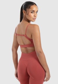 Ribbelige roestkleurige sportbeha met verstelbare bandjes en een open rugontwerp. Gepaard met hoge ribbelige leggings in bijpassende kleur.