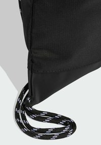 Black fabric backpack with a textured surface and a durable, solid bottom. Features black-and-white braided cord straps for carrying.