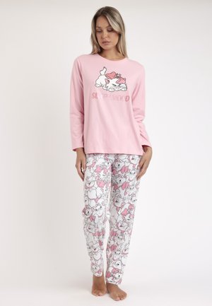 Mujer que lleva una camiseta de manga larga rosa con un gato de dibujos animados y texto 'sleep', combinada con pantalones de pijama blancos con caras repetidas de gatos de dibujos animados con lazos.