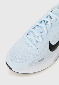 Hellblaue Sportschuh mit strukturiertem Stoff und schwarzem Nike-Logo, ausgestattet mit detaillierter Schnürung und einer gepolsterten Sohle.