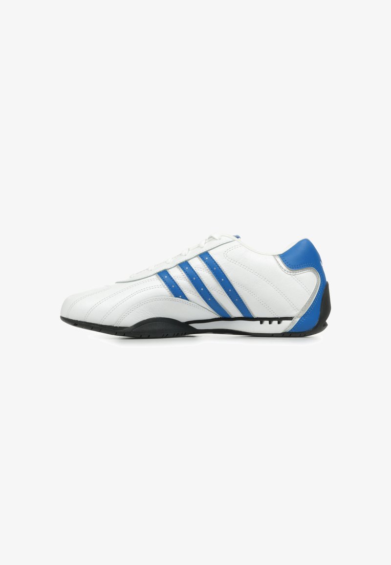 Baskets blanches de sport avec trois rayures bleues, dessus en cuir lisse, bout arrondi et semelle en caoutchouc noir avec des détails de grip.