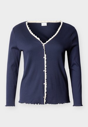 Granatowy, długi kardigan z kieszeniami, ozdobiony białą falbanką wzdłuż dekoltu w serek, guziczków, mankietów i dolnego brzegu.