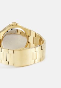 Gouden roestvrijstalen horloge met een geborstelde afwerking, schakelsluiting, klittenbandslot en een ronde kast. Voert logo-engraving op de sluiting.