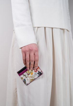 Kartenetui mit Blumenmuster und Akzenten in Pink und Schwarz, aus strukturiertem Material, in einer Hand gehalten, vor einem hellen Hintergrund.