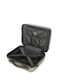 Maleta rígida gris de forma rectangular, con interior dividido, correas ajustables para un embalaje seguro y forro de tela negra con bolsillos.