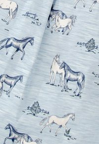 Tissu bleu clair avec des chevaux esquissés dans diverses poses, agrémenté d'accents herbeux et d'un dessin de clôture simple en arrière-plan.