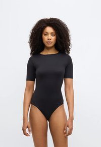 Μαύρο κορμάκι με κοντ ά μανίκια και στρογγυλή λαιμόκοψη, κατασκευασμένο από απαλό, ελαστικό υλικό· εφαρμοστή γραμμή με ψηλή κοπή στα πόδια.