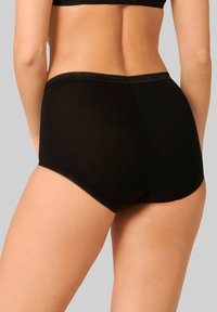 Slip in cotone nero caratterizzato da una texture liscia, design alto e pizzo lungo l'elastico. Sottogarma semplice e senza cuciture.