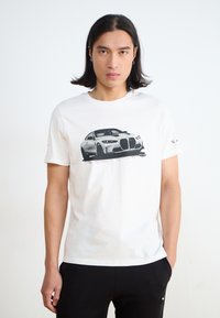 Biała bawełniana koszulka T-shirt z grafiką czarnego samochodu. Krótkie rękawy, okrągły dekolt, luźny krój. Gładkie tło bez wzorów czy akcentów.