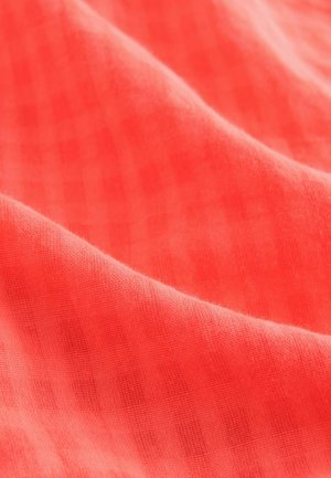 Korálová tkanina s hladkou strukturou, s jemným kostkovaným vzorem. Materiál se zdá být lehký a mírně průsvitný.
