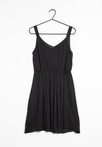 Svart ärmlös klänning med V-ringning, elastisk midja och flödande kjol. Tillverkad av lättviktsmaterial med en mjuk textur. Hänger på en svart krok.