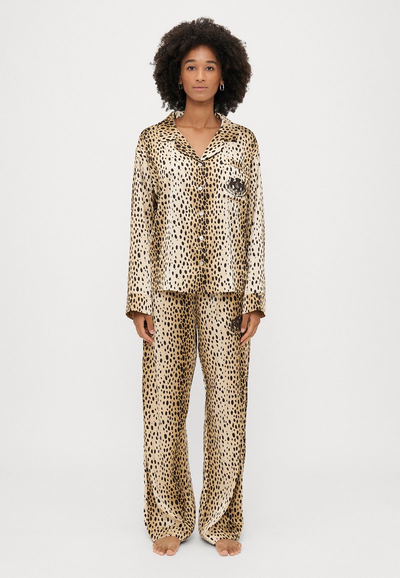Set de pijamale din satin cu imprimeu de leopard, format dintr-o cămașă cu nasturi și pantaloni largi, având un buzunar pe piept, în nuanțe de crem și negru.