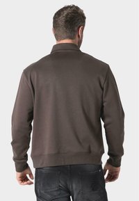 Felpa con zip marrone, dotata di colletto, polsini e orlo a coste. Tessuto liscio, design semplice e vista posteriore unica.