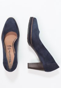 Námornické semišové lodičky s kulatou špičkou, texturovaným dřevěným blokovým podpatkem a jemným prošíváním na svrchní části.