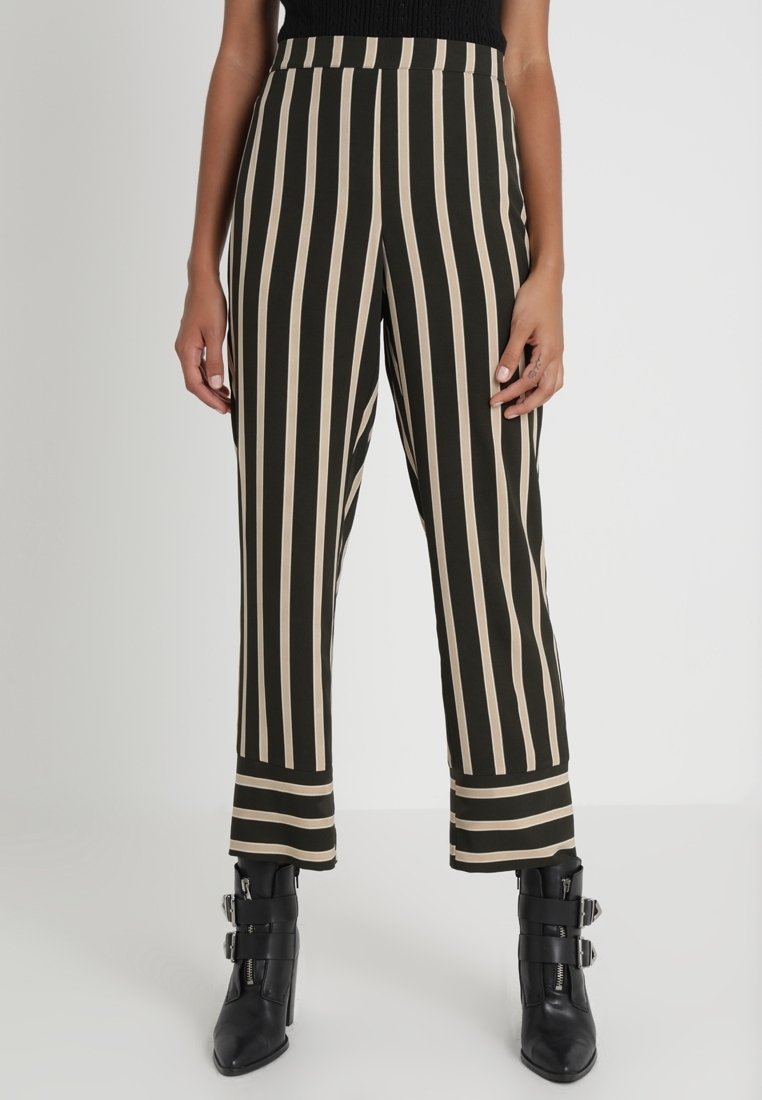 Pantalon à rayures noires et beige avec une taille haute et une coupe évasée. Tissu lisse, présentant des rayures verticales audacieuses et des détails au niveau de l'ourlet.