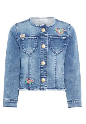 Blaue Jeansjacke mit ausgefransten Rändern, goldenen Knöpfen vorne, zwei Brusttaschen und kleiner Blumenstickerei auf der Brust sowie am unteren Rand.