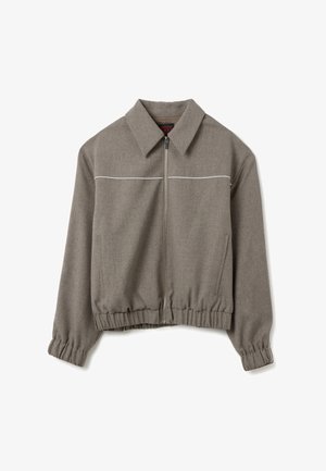 Grijze zip-up jas met gespreide kraag, elastische manchetten en zoom, twee voorkruiken en witte horizontale piping over de borst.