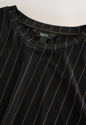 Schwarzes Oberteil mit vertikalen goldenen Streifen, rundem Ausschnitt, weichem Stoff, mit subtiler Textur und einem Etikett mit der Aufschrift "NEXT".