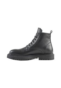 Botas de tobillo de cuero negro con un diseño de cordones, puntera redondeada y una suela de goma negra gruesa con dibujos profundos para mayor tracción.