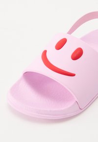Rózsaszín csúszda, piros mosolygós arc mintával a pánton. Simább szintetikus anyagból készült, texturált talpbélése a kényelem érdekében.