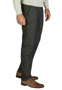 Dunkelgraue Hosen mit strukturiertem Finish, seitlichen Taschen, taillierter Passform und getragen mit braunen Lederschuhen.