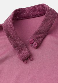 Halenka s golierom v jednofarebnej fialovej látke, s textúrovaným golierom so striebornými trblietkami a so svojimi dvoma okrúhlymi gombíkmi v ladenej fialovej farbe.