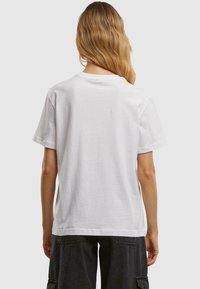 White cotton t-shirt with a relaxed fit, short sleeves, and a crew neckline. No visible graphics or patterns on the back.