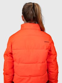 Oseba s spetimi lasmi nosi svetlo oranžno oblazinjeno jakno z visokim ovratnikom, ki vsebuje majhen črn logotip "Brunotti" na rami.