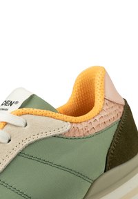 Groene sneaker met beige suède en gestructureerde roze accenten. Voorzien van een mesh gele voering, witte veters en een gevoerde zool.