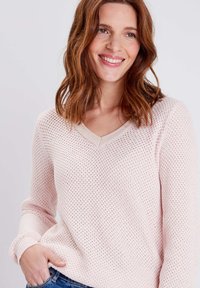 Hellblauer gestrickter Pullover mit V-Ausschnitt, der ein strukturiertes Muster und gerippte Bündchen aufweist. Der Stoff ist atmungsaktiv und locker geschnitten.