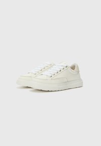 Weiße Sneakers aus glattem Leder mit runder Spitze, flachen Schnürsenkeln und einer strukturierten Sohle. Mit silbernen Ösen und einer weichen Innenauskleidung.