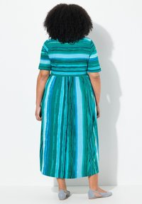 Maxi sukienka w odcieniach zieleni i niebieskiego z poziomymi paskami. Krótkie rękawy i zebrana talia z luźną spódnicą. Połączona z jasnoniebieskimi balerinami.