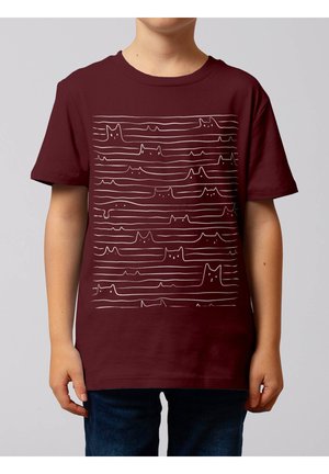 Kind draagt een bordeauxrode T-shirt met witte lijntekeningen van meerdere kattenkoppen en -poten, gerangschikt in horizontale rijen.