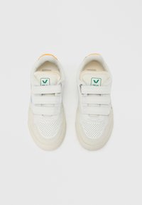 Valged vabaajajalatsid takjakinnitusega, tekstureeritud pooridega varbarea, sinine küljeaksent ja oranž kandminekriips. Disainitud kaubamärgiga logoga detailiga.