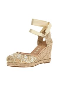 Espadrilles de cuña beige con parte superior de tela tejida, que presentan detalles bordados en blanco y correas en crema para el tobillo. Diseño de punta cerrada texturizada.