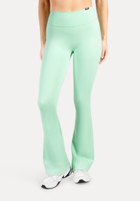 Leggings évasés vert menthe en tissu extensible avec une taille haute. Caractérisés par une texture lisse et un branding minimaliste sur la ceinture.
