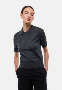 Polo en tricot gris foncé à manches courtes avec un col classique, une coupe ajustée et un ourlet côtelé, fabriqué en tissu texturé doux.
