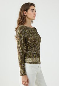 Haut marron à manches longues avec un design texturé et à motifs dans des teintes jaunes et vertes ; légèrement froncé à la taille, tissu transparent, encolure ronde.