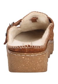 Brown suede clog with a wool-lined interior, sturdy tan platform, and contrasting white stitching along the edges. Adjustable buckle detail.