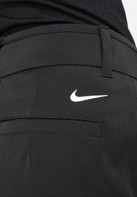 Melni sporta šorti ar gludu tekstūru, kuriem ir aizmugurējā kabata un balts Nike swoosh logo labajā pusē.